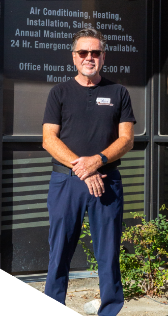 Man standing in front of Priority One Air Conditioning and Heating office, wearing sunglasses and a black polo shirt, showcasing the company's HVAC services and commitment to customer care.